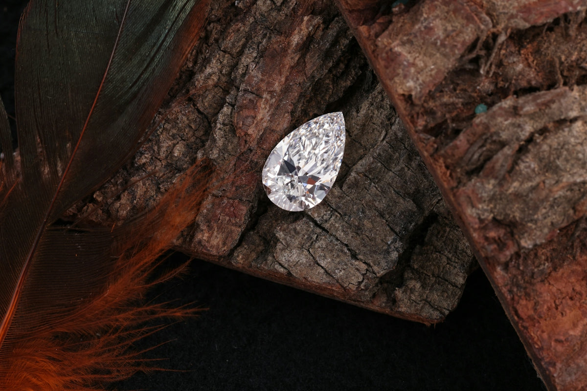 A pear-shaped diamond rests on wood.