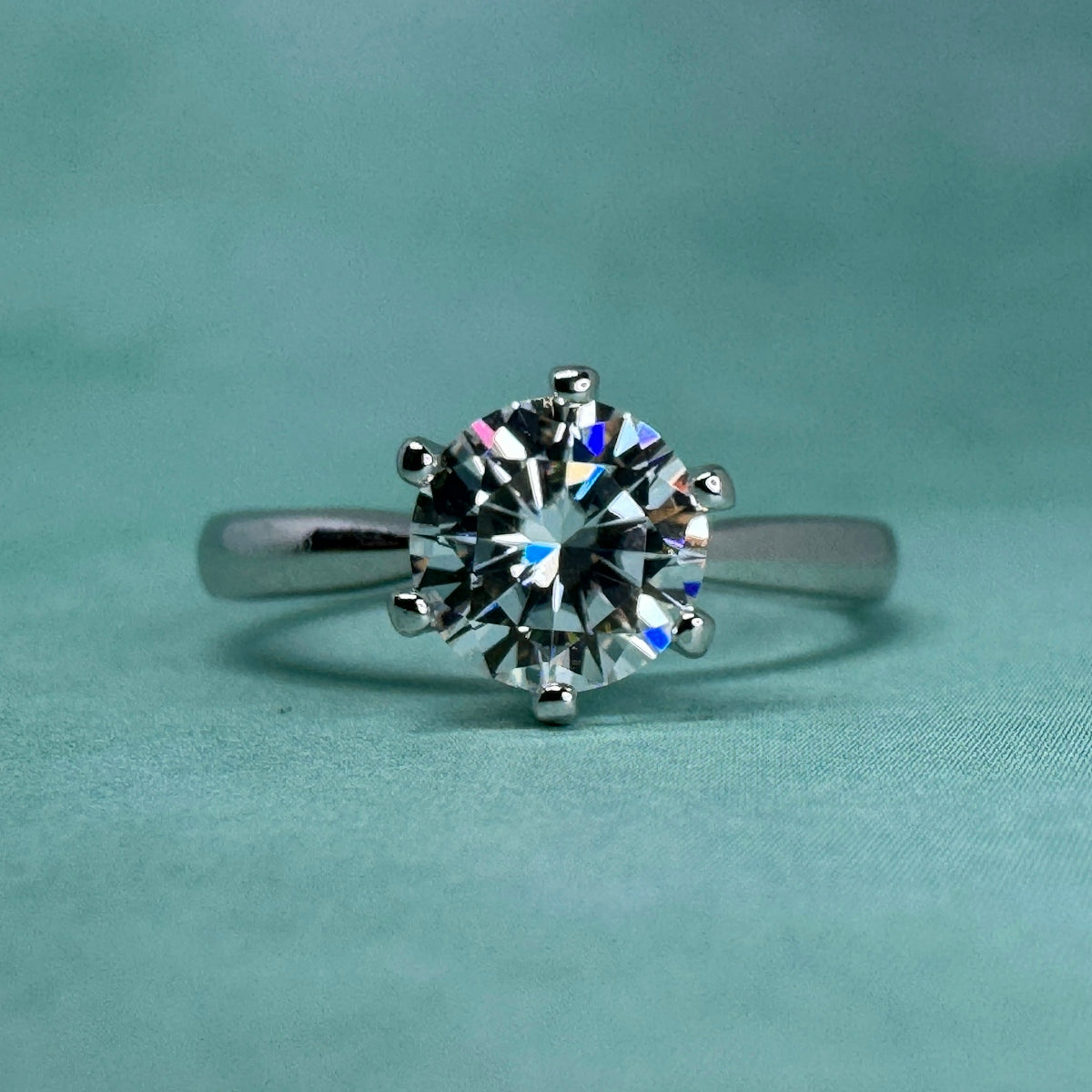 A sparkling diamond ring on a teal background