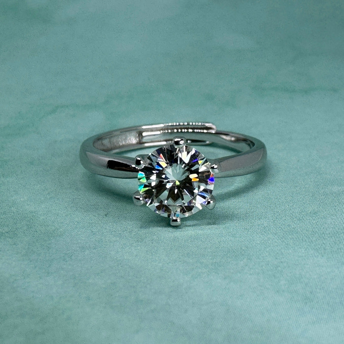 A diamond engagement ring on a teal background